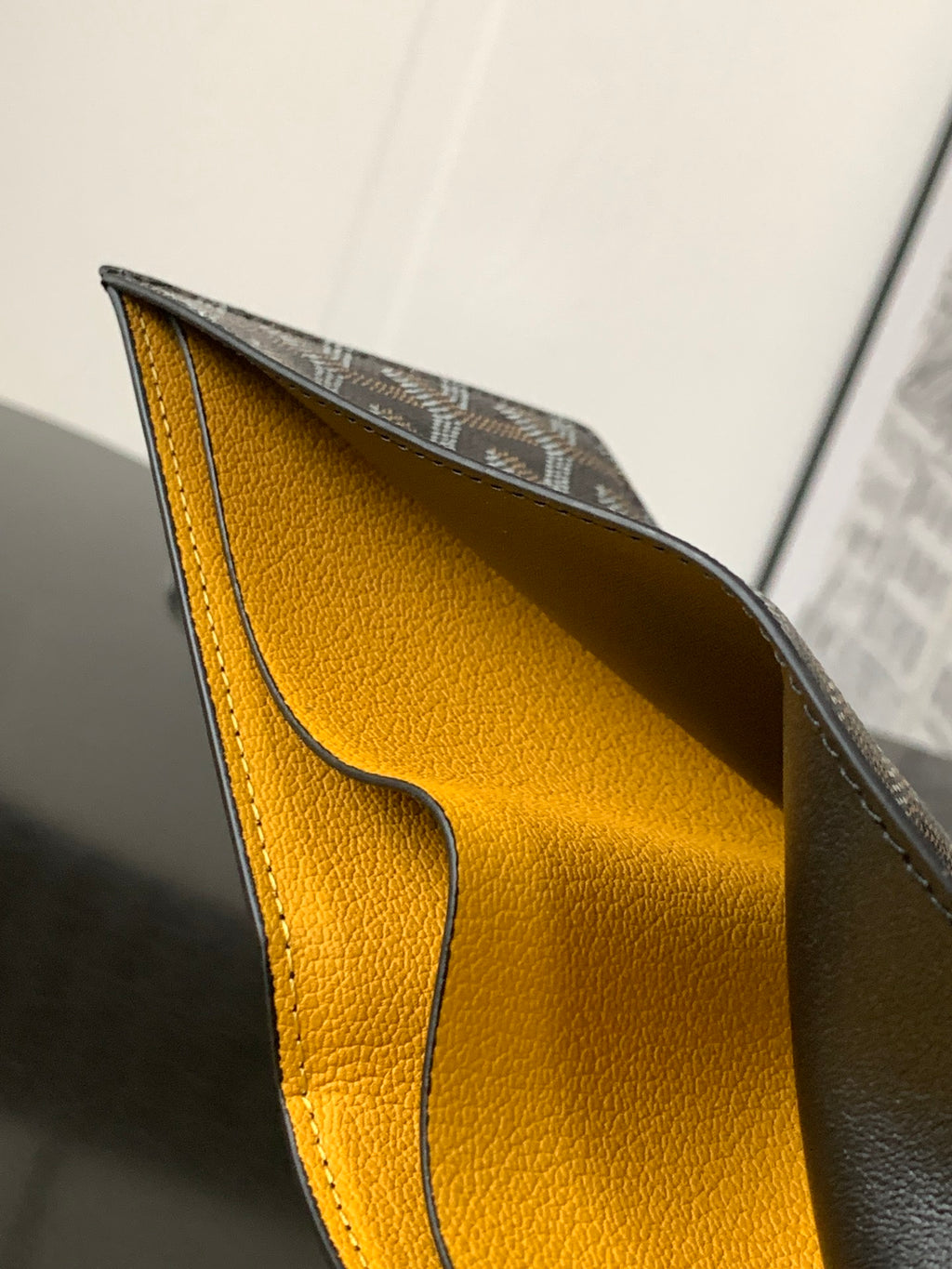 Leather wallet interior with bright yellow lining and curved seam