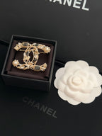 Ornate gold-tone brooch with faux pearls and dark gemstone accents, shown in gift box
