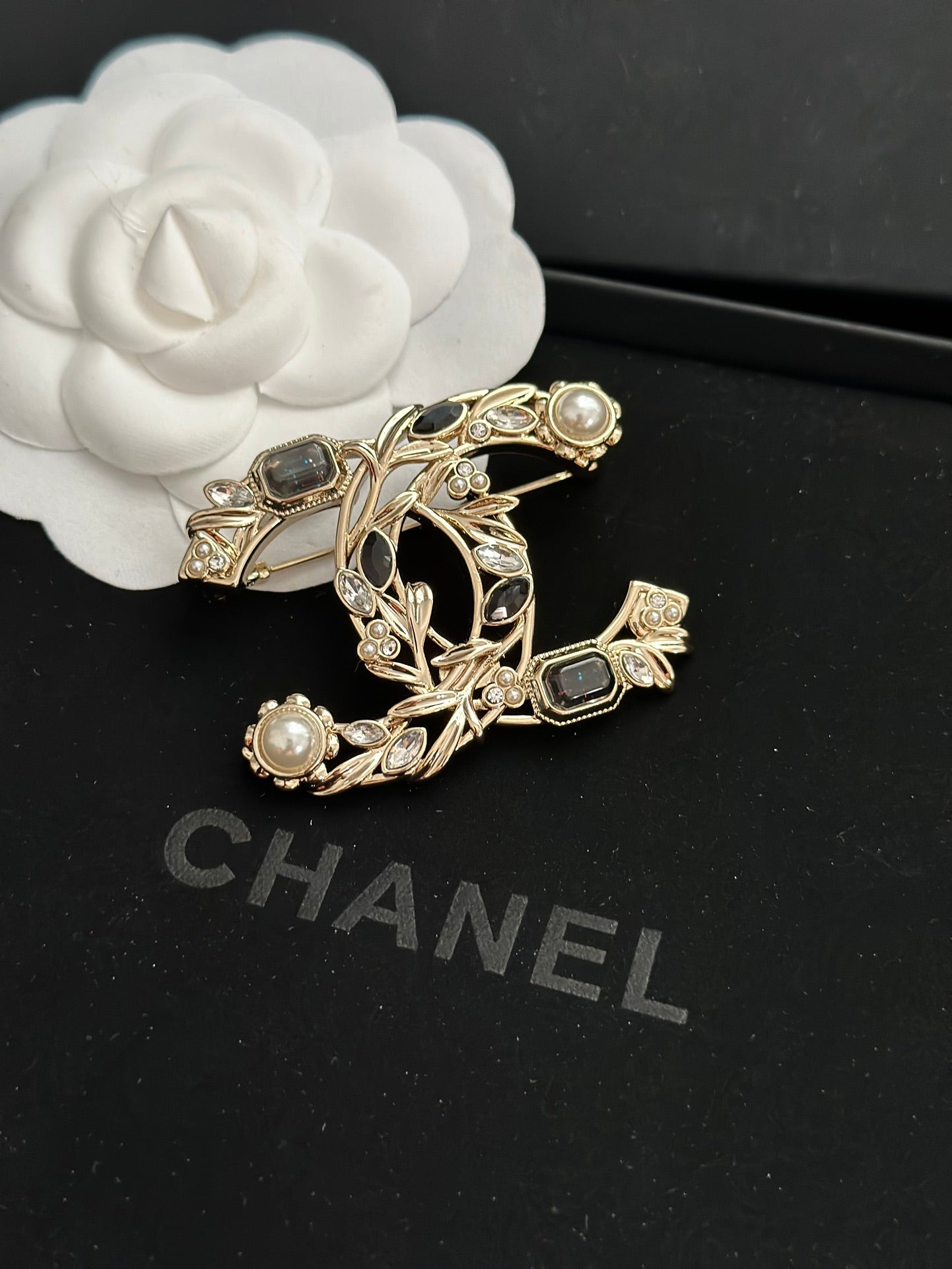Ornate gold-tone brooch with faux pearls and dark gemstone accents, leaf-and-vine design