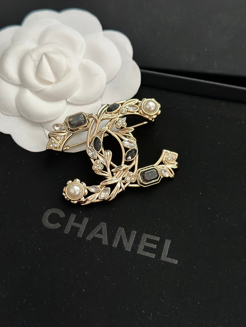 Ornate gold-tone brooch with faux pearls and dark gemstone accents, leaf-and-vine design