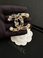 Gold-tone brooch with faux pearls and dark gemstone accents on black fabric backing