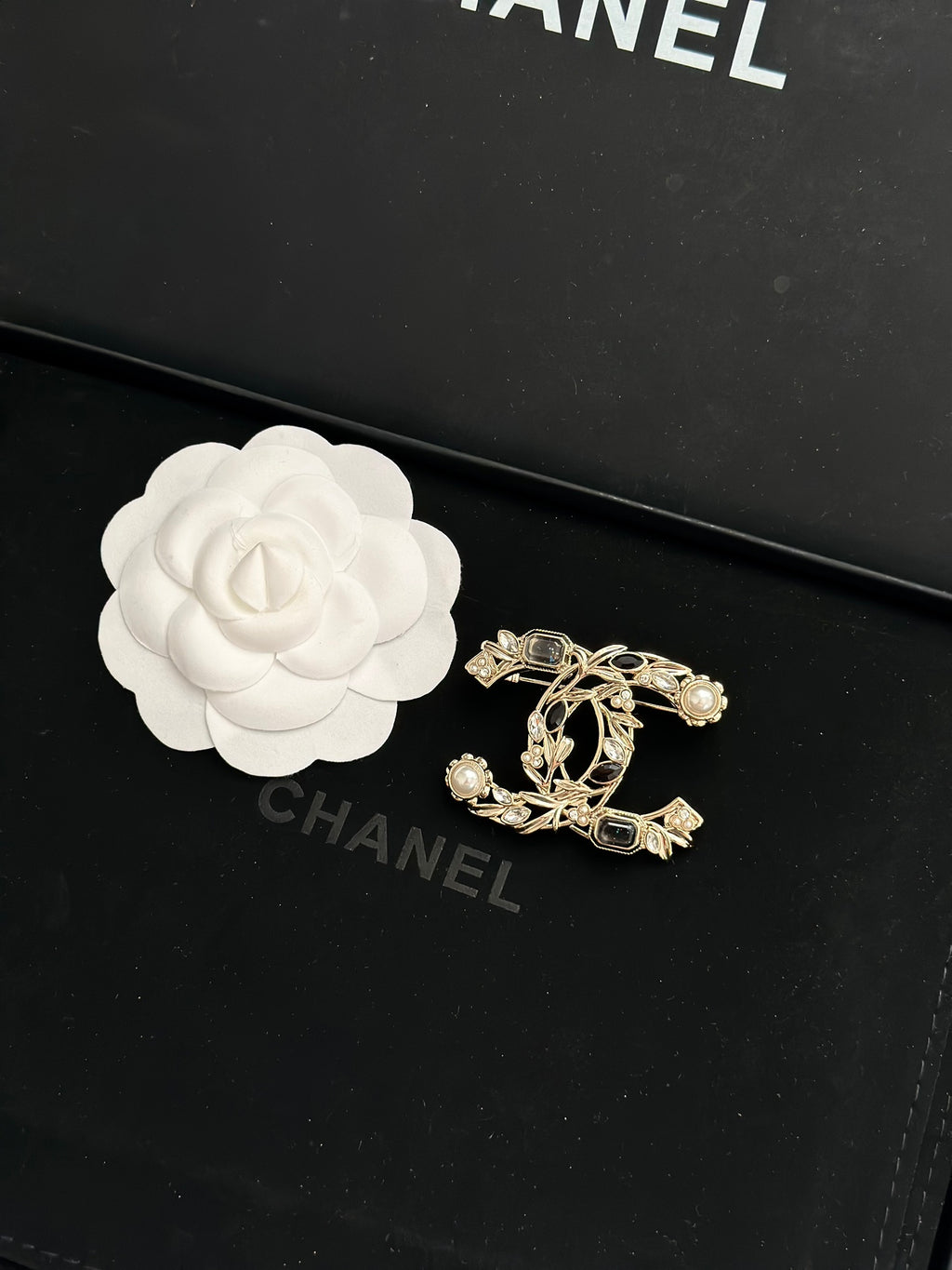 Gold-tone brooch with faux pearls and dark gemstone accents in a decorative emblem design