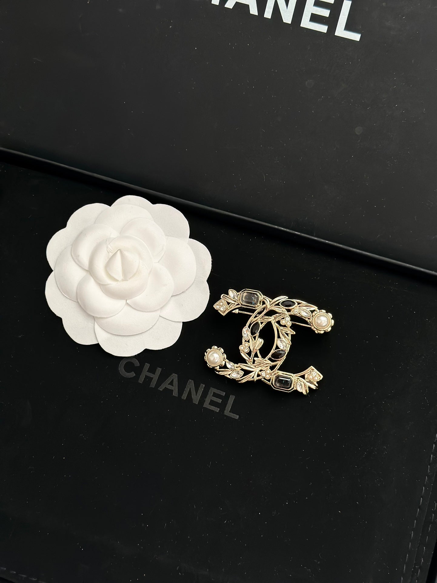 Gold-tone brooch with faux pearls and dark gemstone accents in a decorative emblem design