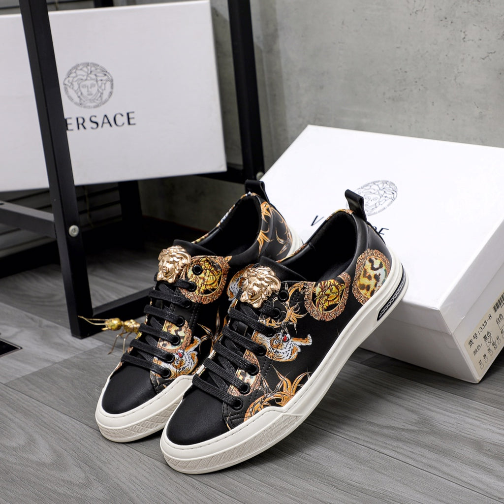 Pair of black low-top sneakers with gold baroque animal motifs and white soles