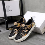 Pair of black low-top sneakers with gold baroque animal motifs and white soles