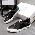 Versace black low-top sneakers with gold crest hardware, green/red stripe, and white sole