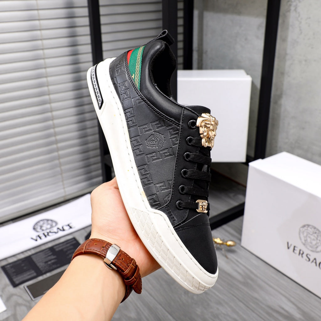 Versace black low-top sneakers in hand, gold crest on lace, green stripe panel, white sole
