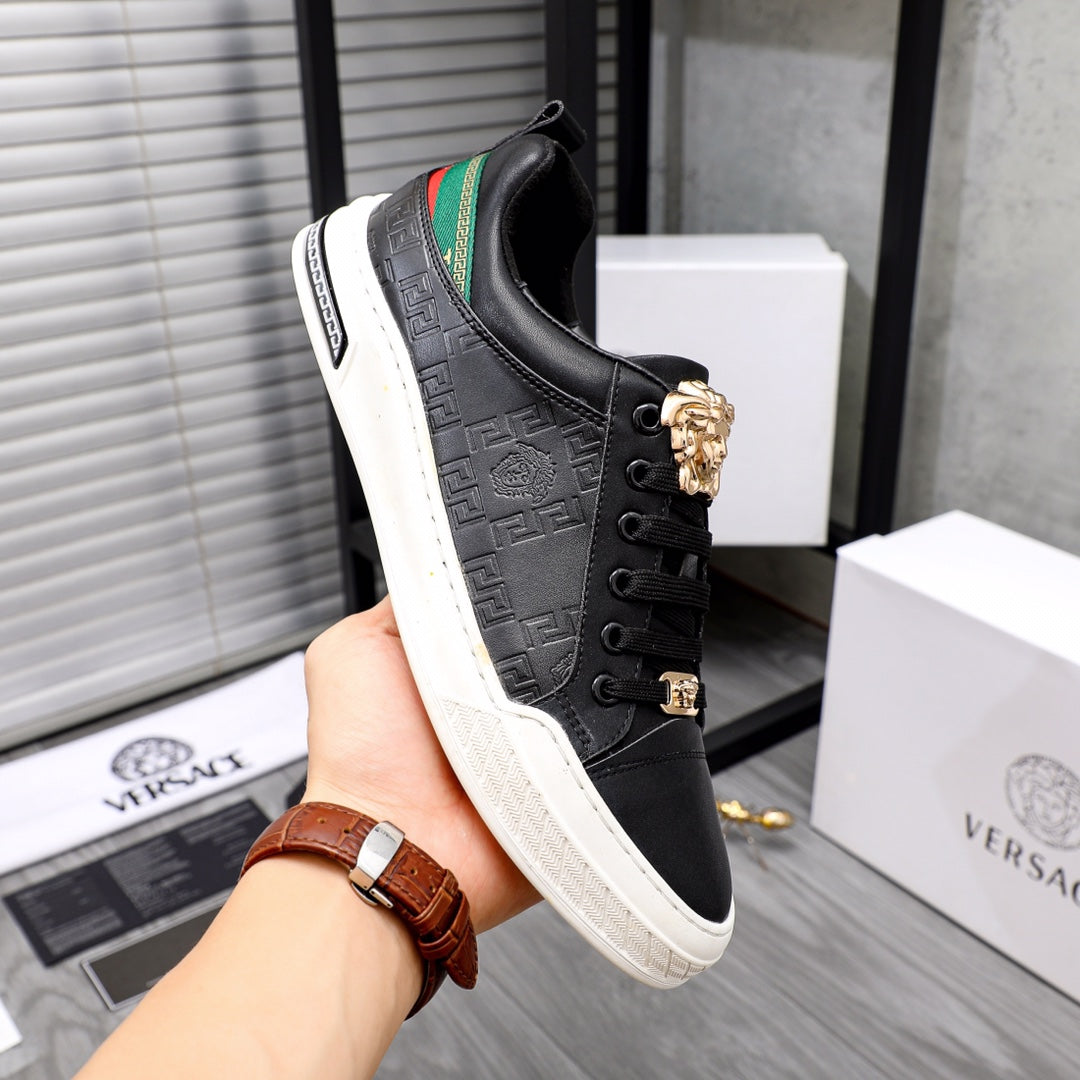 Versace black low-top sneakers in hand, gold crest on lace, green stripe panel, white sole