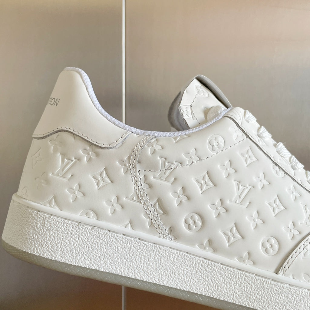 White LV monogram sneaker with embossed floral motifs and textured rubber sole edge.