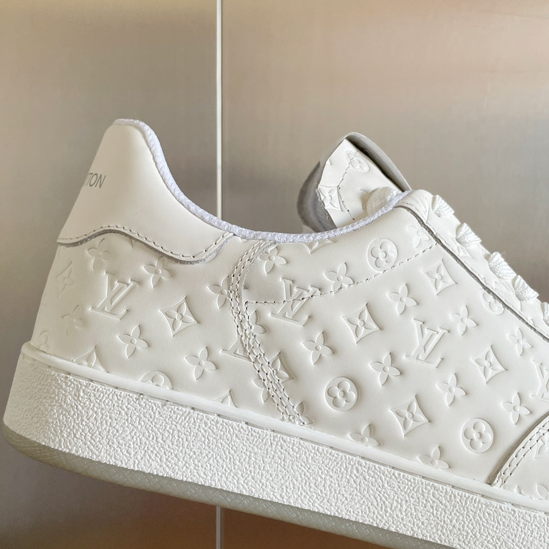 White LV monogram sneaker with embossed floral motifs and textured rubber sole edge.