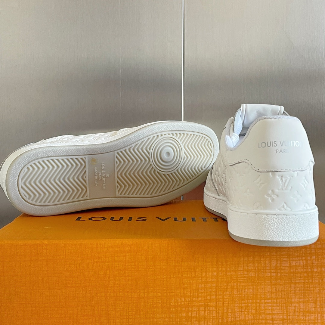 White sneakers with rubber outsole tread and embossed LV logo on heel.