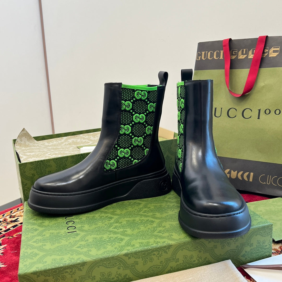 Black Chelsea boots with neon green GG-pattern elastic, stacked angle view.