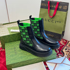 Pair of black Chelsea boots with neon green GG-pattern elastic cuffs.