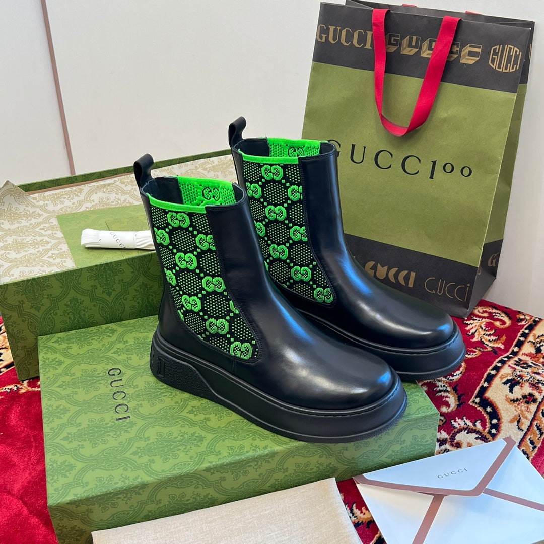 Pair of black Chelsea boots with neon green GG-pattern elastic cuffs.