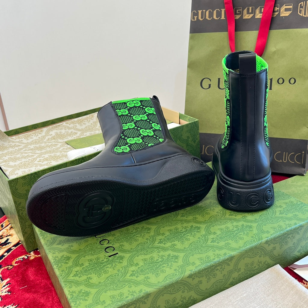 Black Chelsea boots with neon green GG-pattern elastic, rubber sole visible.