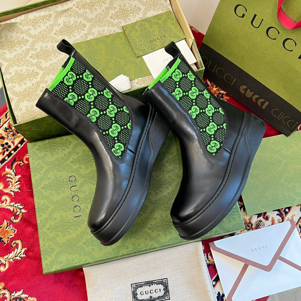 Black Chelsea boots with neon green GG-pattern elastic panels, top view.