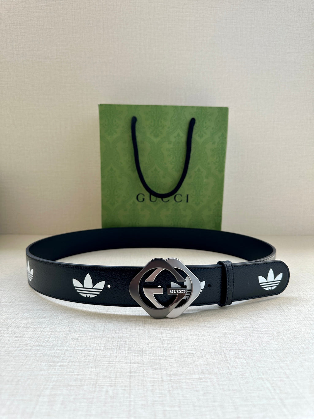Gucci belt on surface with dark navy leather, white trefoil logos, and silver-tone buckle