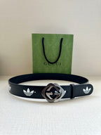 Gucci belt on surface with dark navy leather, white trefoil logos, and silver-tone buckle