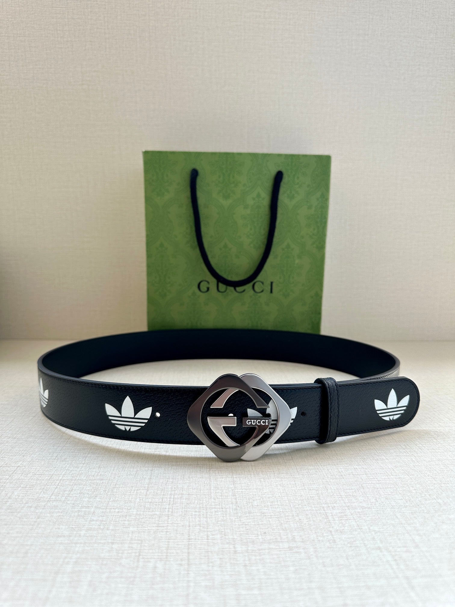Gucci belt on surface with dark navy leather, white trefoil logos, and silver-tone buckle