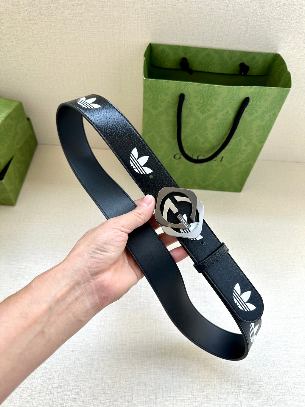 Gucci belt held up: dark navy strap with white trefoil logos and round buckle