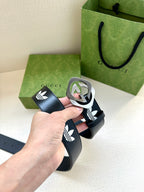Gucci belt close-up on hand grip: dark navy strap, white trefoil logos, round buckle