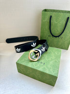 Gucci belt laid flat with dark navy strap, white trefoil emblems, and metal buckle