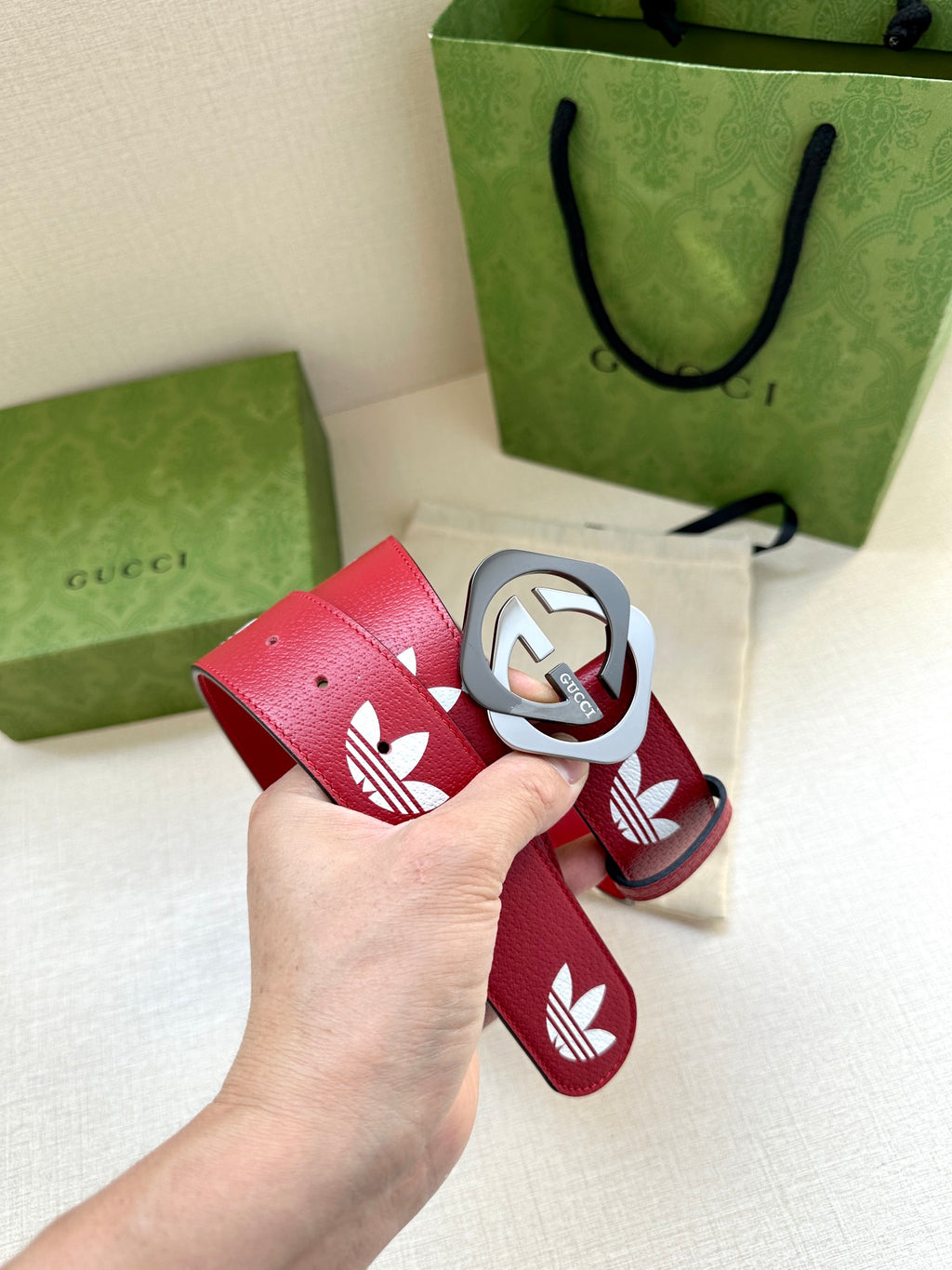 Red Gucci belt detail with white trefoil motifs and silver-tone logo buckle