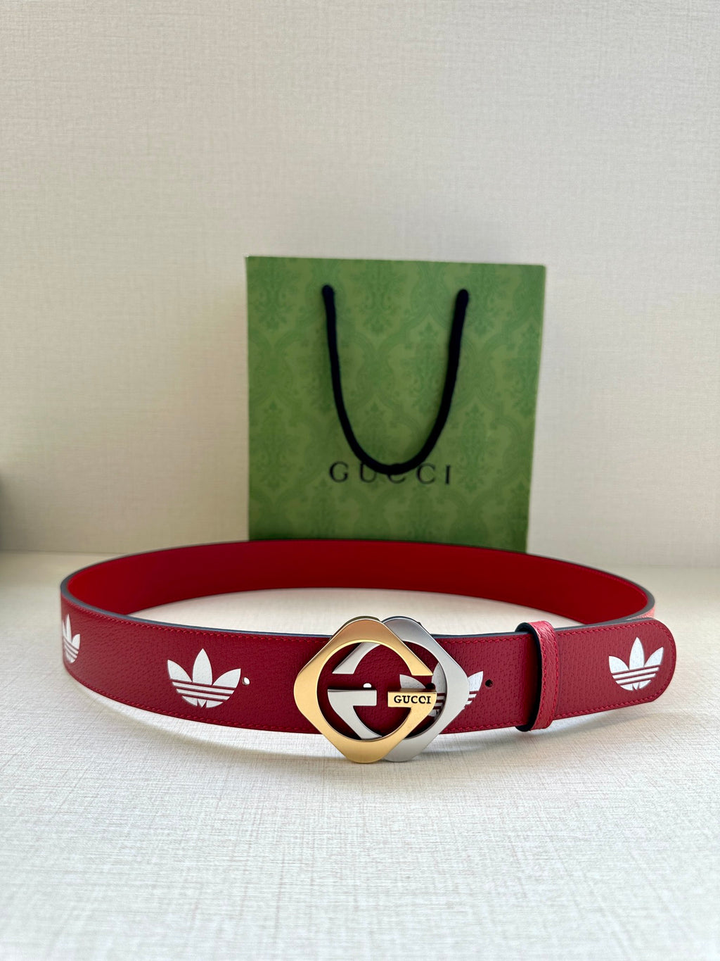 Red Gucci belt with white trefoil print and gold-and-silver round logo buckle