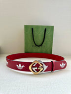 Red Gucci belt with white trefoil print and gold-and-silver round logo buckle