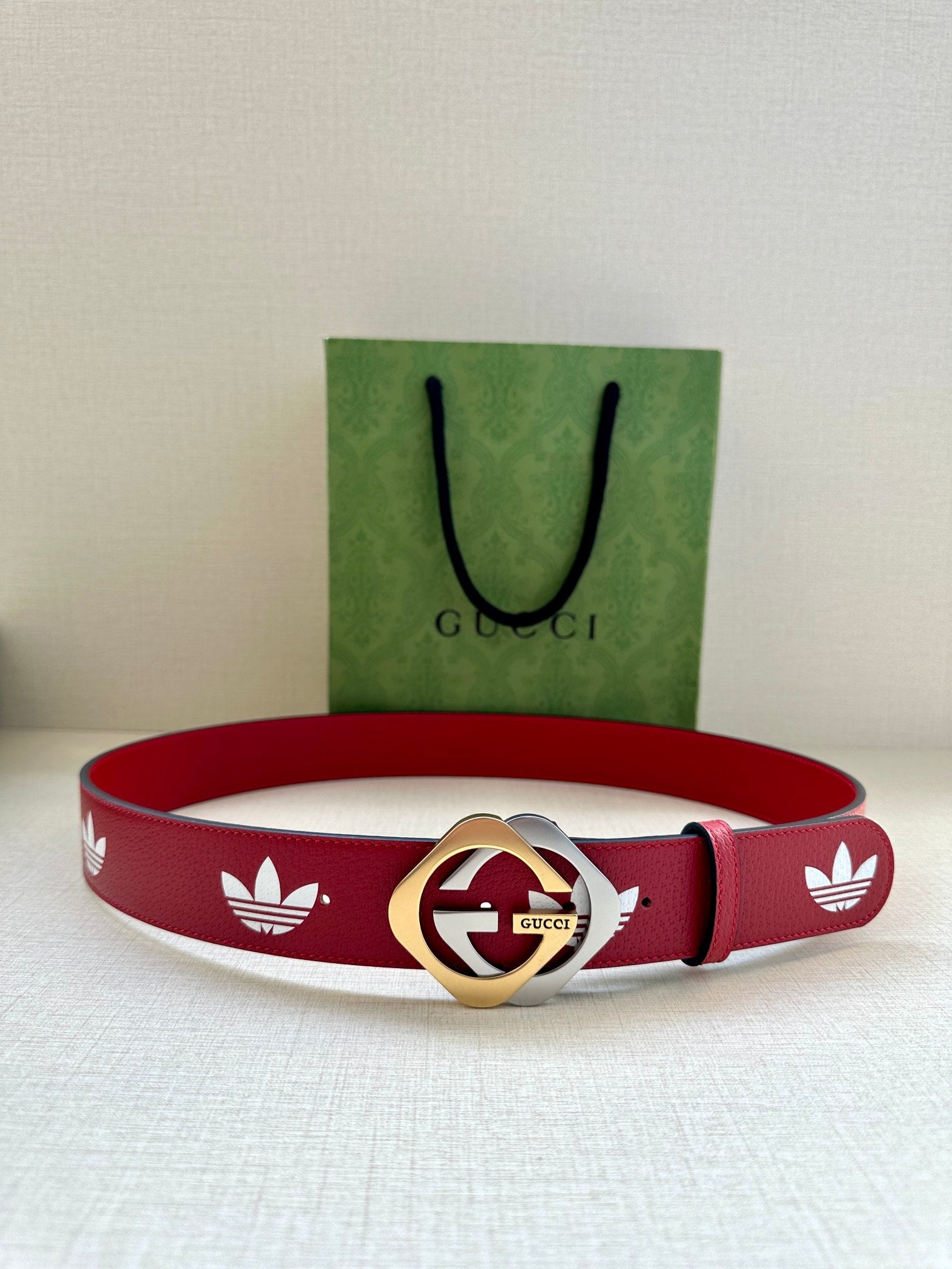 Red Gucci belt with white trefoil print and gold-and-silver round logo buckle