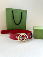Red Gucci belt with white trefoil pattern and gold-and-silver round logo buckle