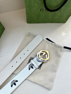 Gucci belt with white leather strap, black logo print, and gold buckle on paper packaging