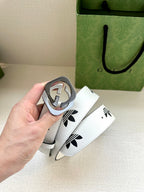 Gucci belt buckle detail with white strap and black logo print, held in hand