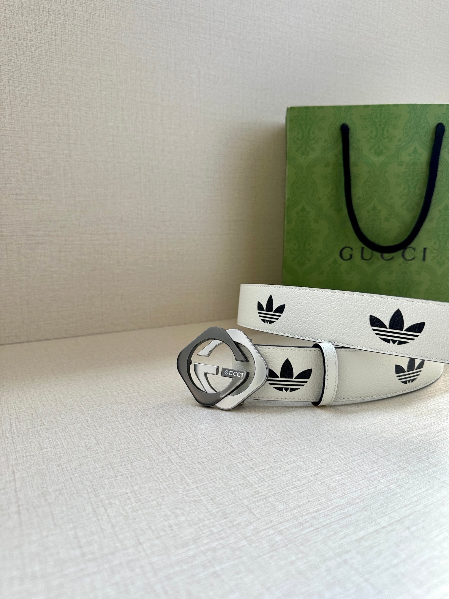 Gucci belt on white surface with black logo print and gold-tone buckle, side view