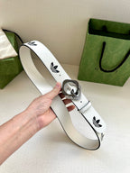 Gucci belt in white leather with black logo print and gold-tone buckle, held in hand