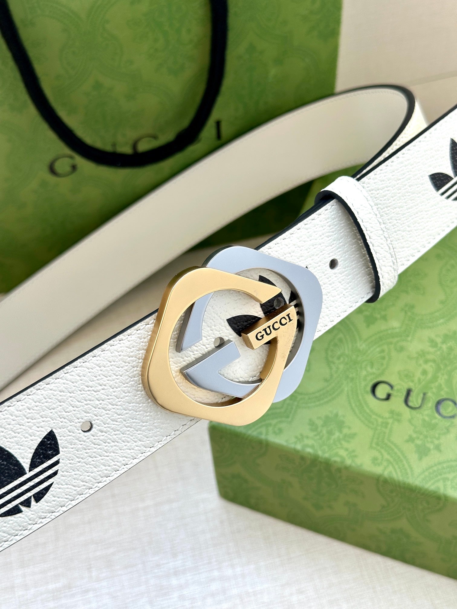 Gucci belt buckle close-up on white leather with black logo print