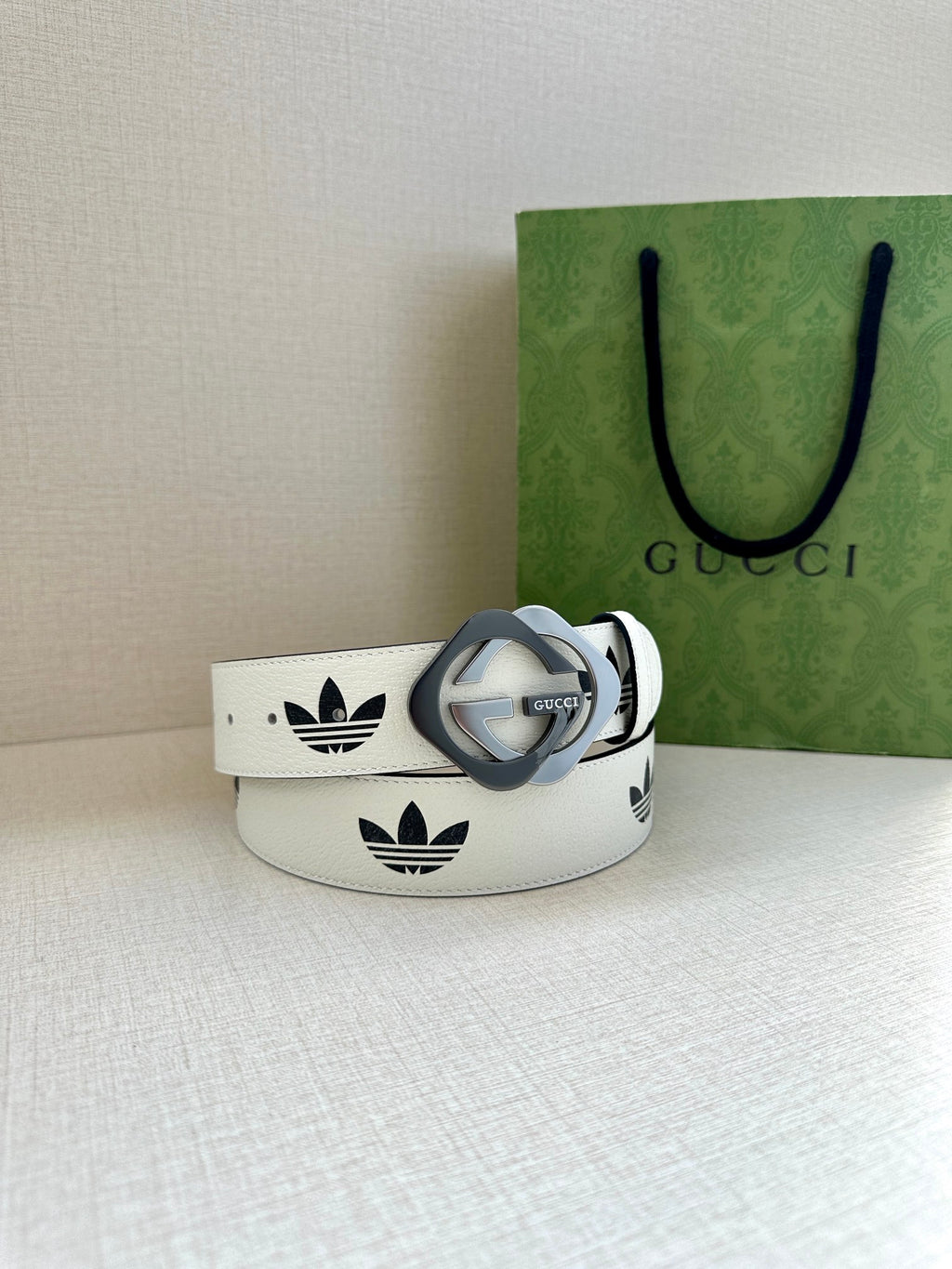 Gucci belt in white leather with black logo print and grey buckle, side profile