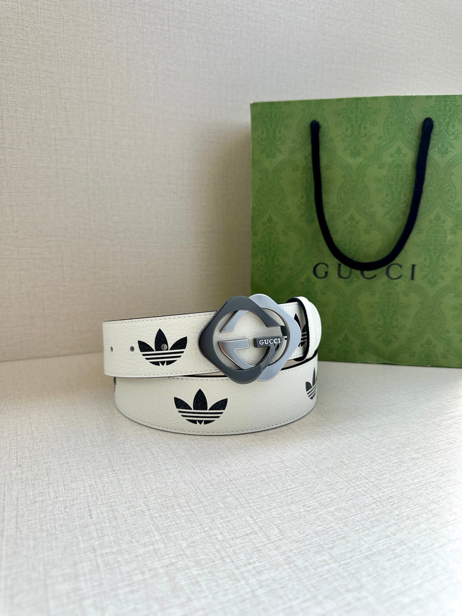 Gucci belt in white leather with black logo print and grey buckle, side profile