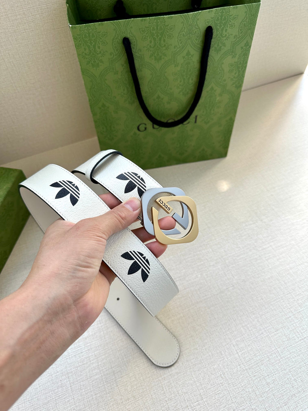 Gucci belt in white leather with black logo print and gold-tone buckle, flat lay
