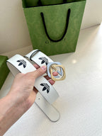 Gucci belt in white leather with black logo print and gold-tone buckle, flat lay