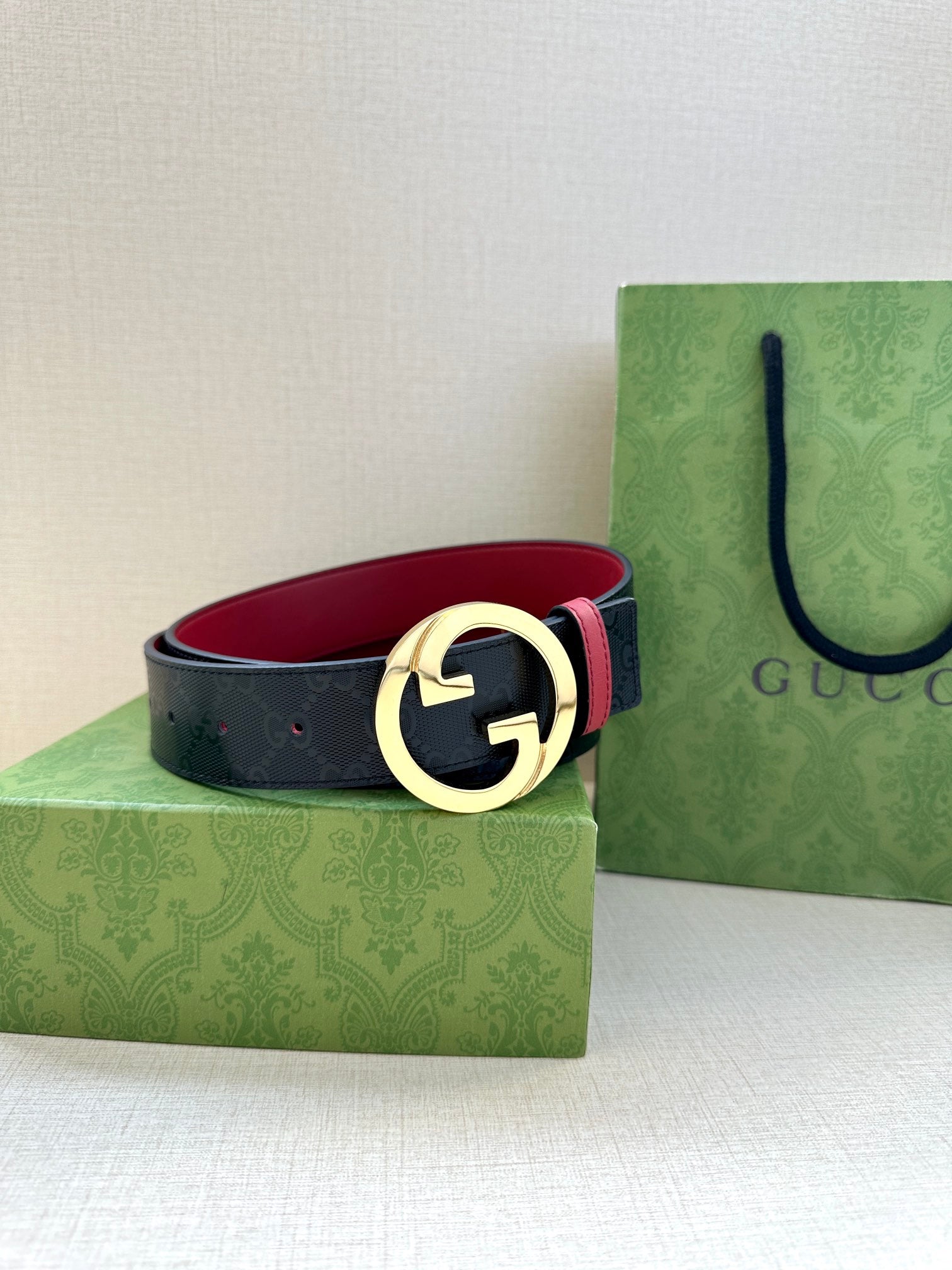 Gucci belt with dark strap, gold-toned G buckle, red underside lining, on box set.
