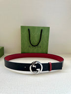 Gucci belt laid flat: dark strap with round silver G buckle and narrow red stripe.
