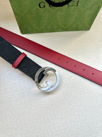 Gucci belt top view: dark monogram strap with red underside, round silver G buckle.