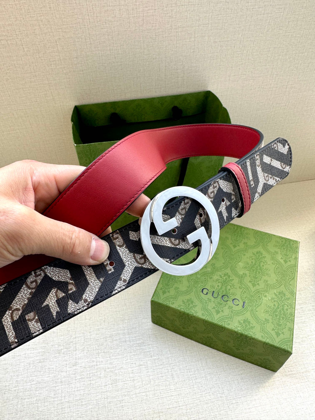 Gucci belt with navy monogram webbing and silver-tone GG buckle, red leather band.