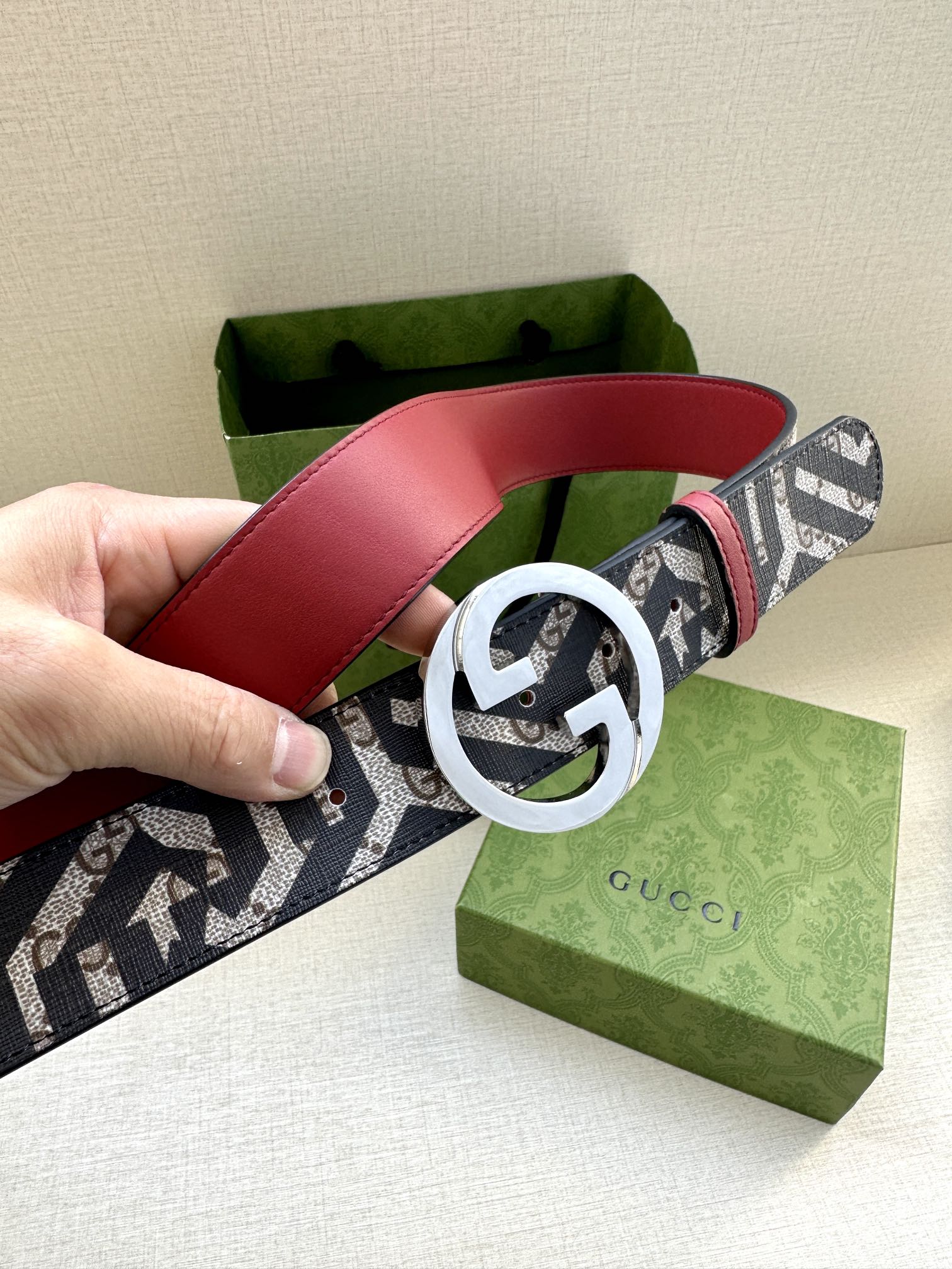 Gucci belt showing red leather strap and navy-and-white logo canvas with GG buckle