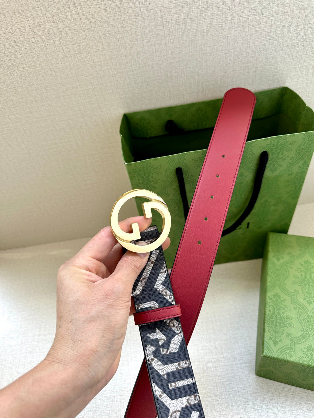 Gucci belt with navy monogram webbing and gold-tone GG buckle, red leather strap.