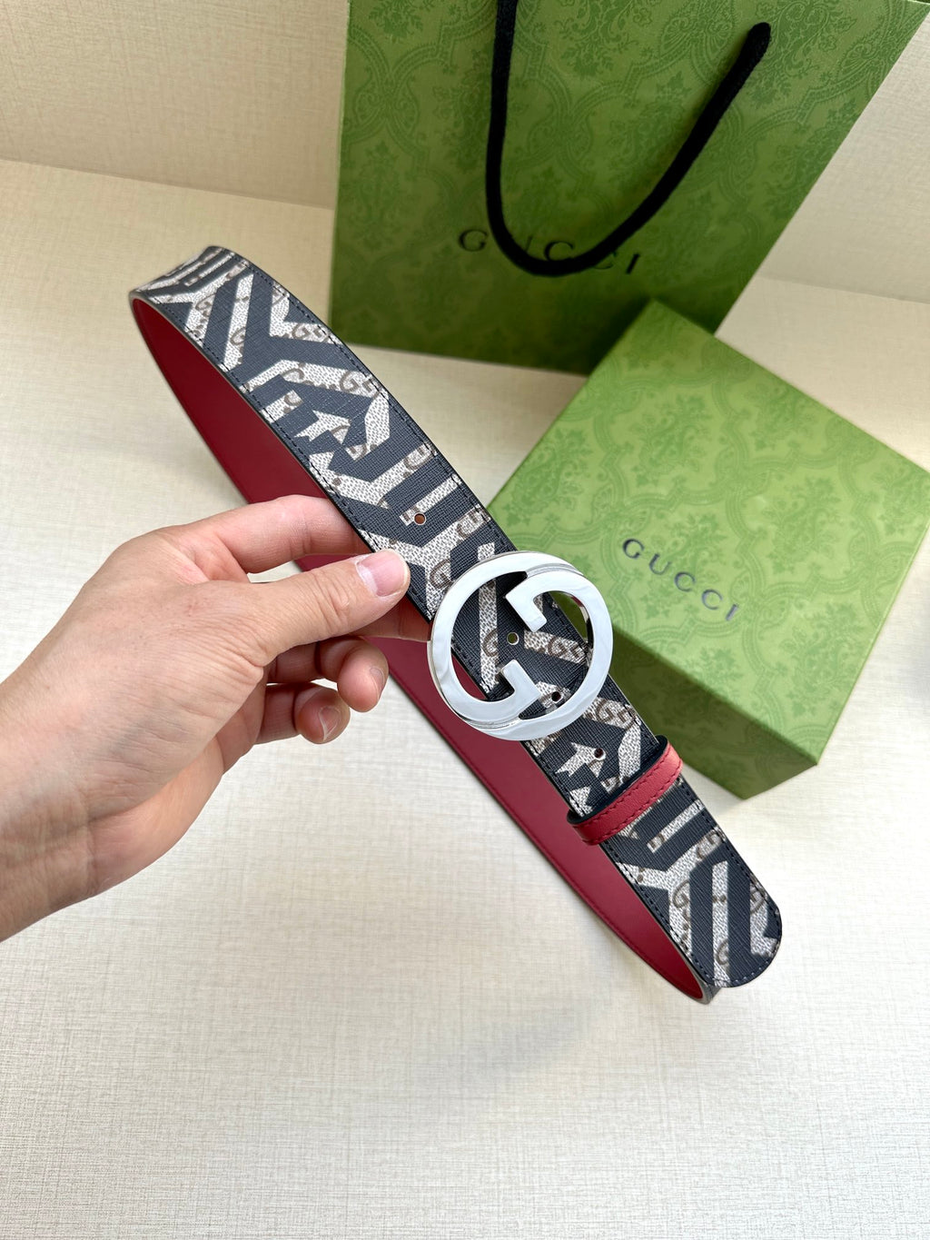 Gucci belt with navy monogram webbing and silver-tone GG buckle, red leather strap.