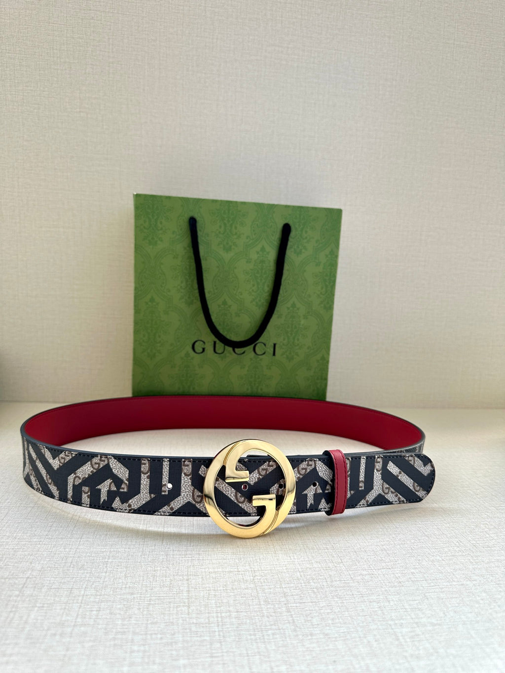 Gucci belt on display: navy-and-white logo canvas with gold-tone GG buckle