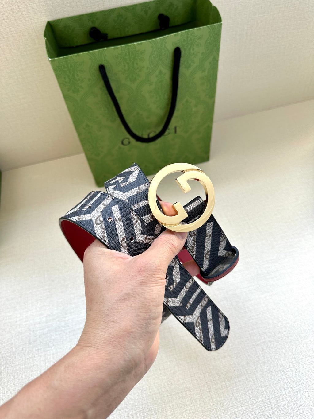 Gucci belt with navy monogram webbing and gold-tone GG buckle, red leather strap.