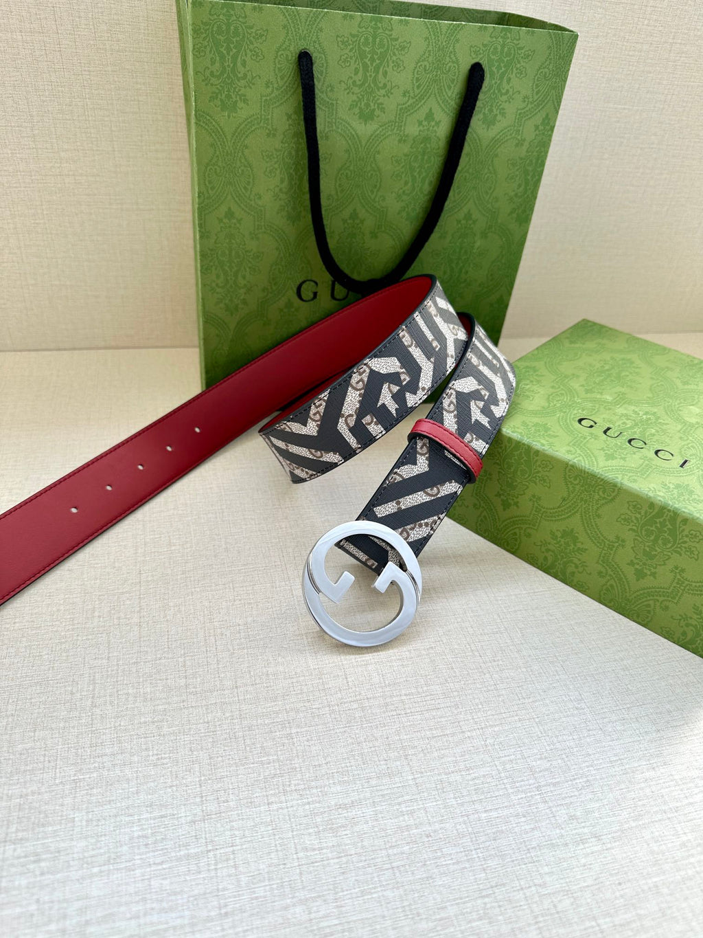 Gucci belt with navy monogram webbing, red leather strap, silver-tone GG buckle.